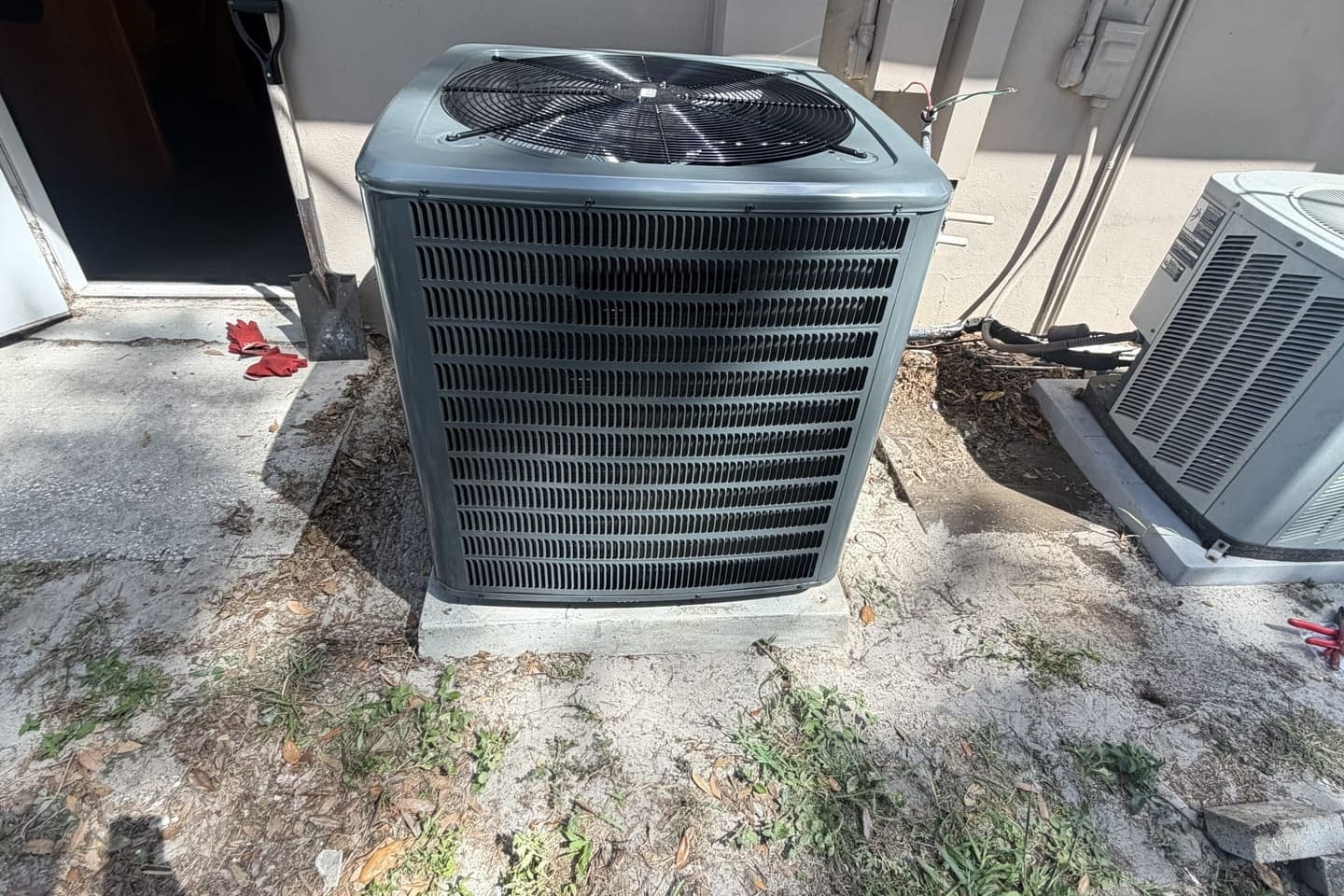 An outdoor condenser with its fan guard beside a second unit.
