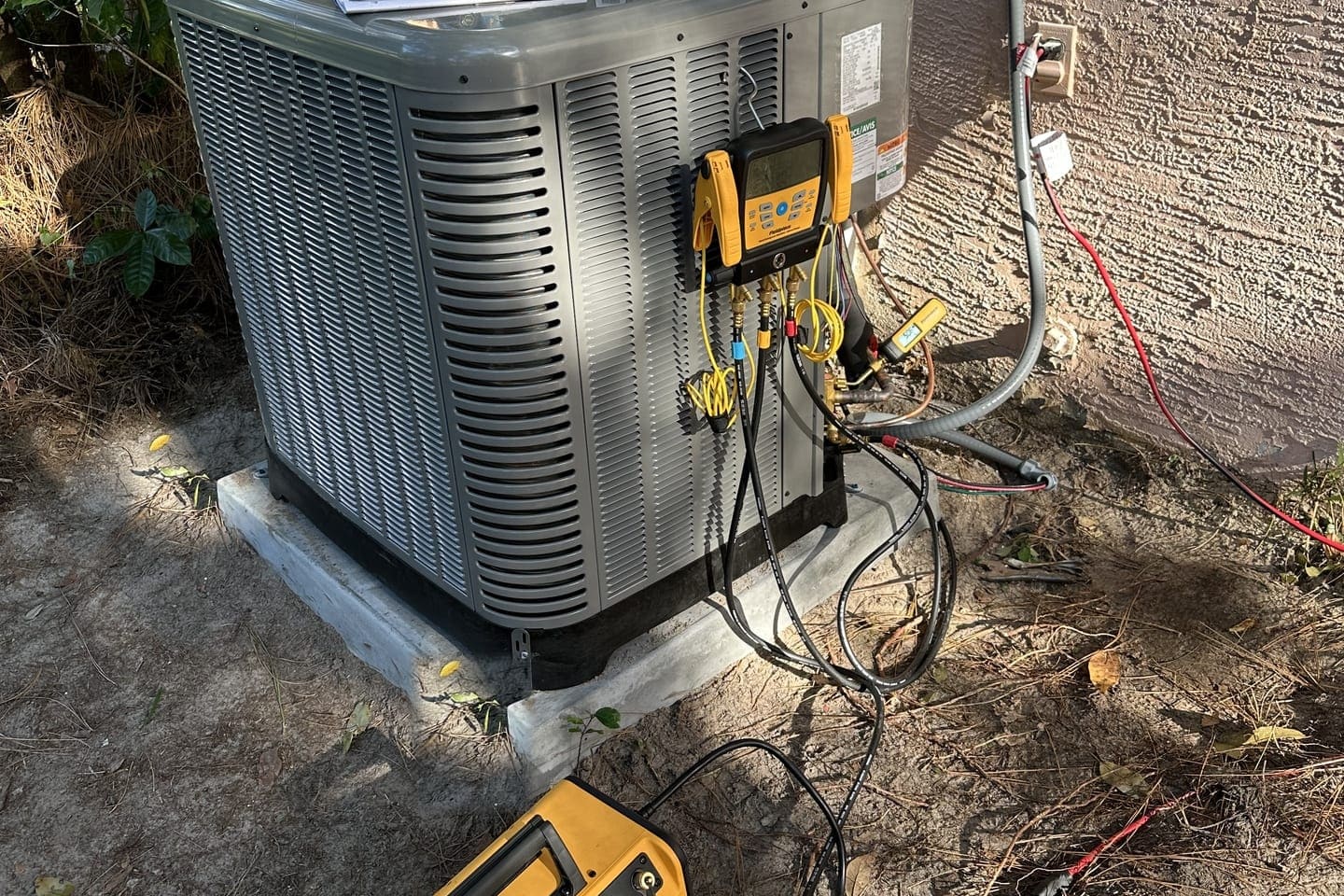 An outdoor condenser with yellow gauge hoses connected for a refrigerant check in Spring Hill, FL.