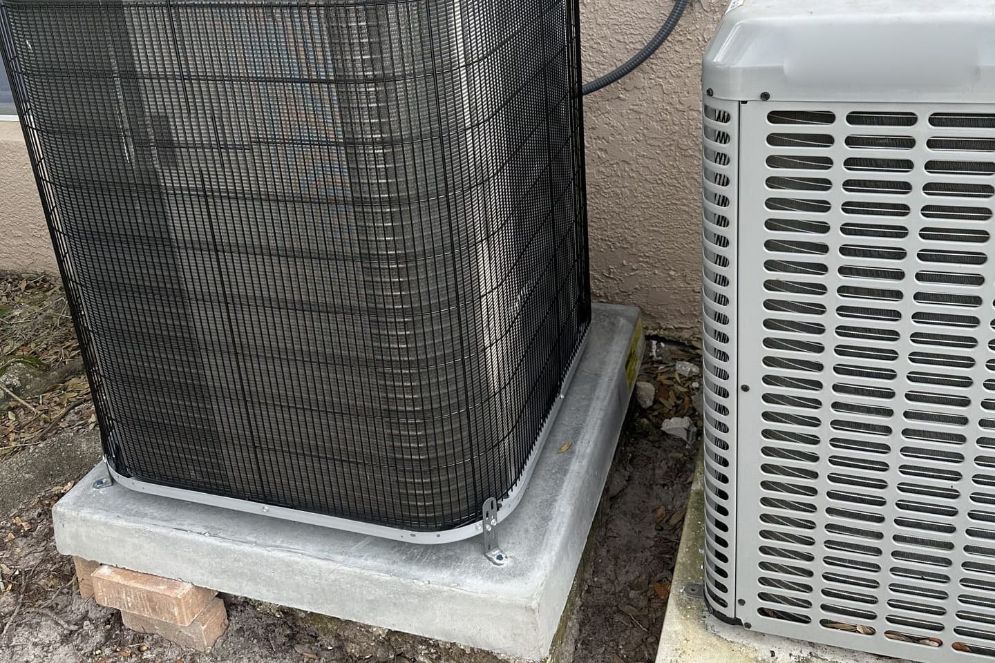 A pair of outdoor condensers beside a stucco wall in Pasco County, FL.