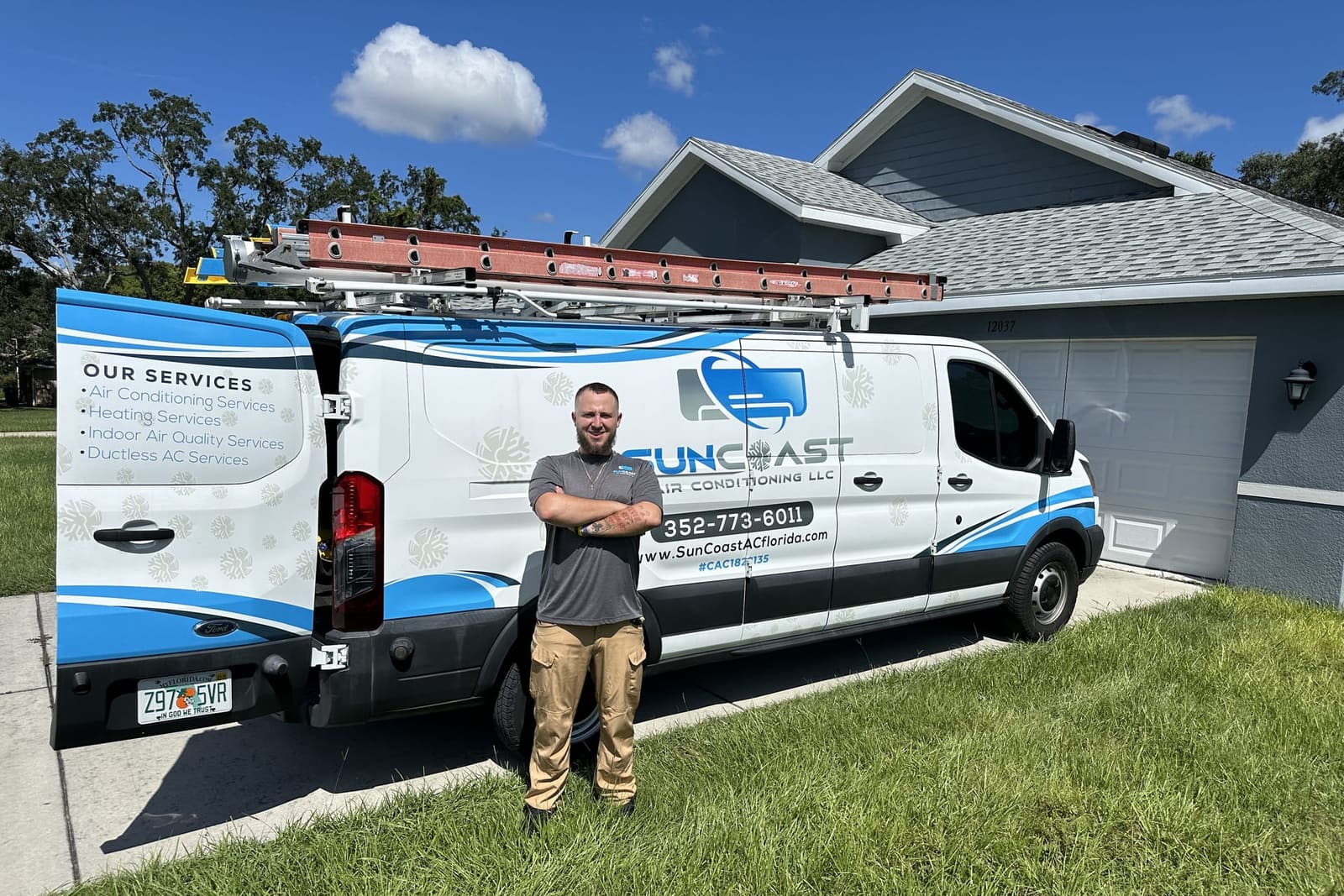 A SunCoast technician posing beside the service van in a driveway in Spring Hill, FL.