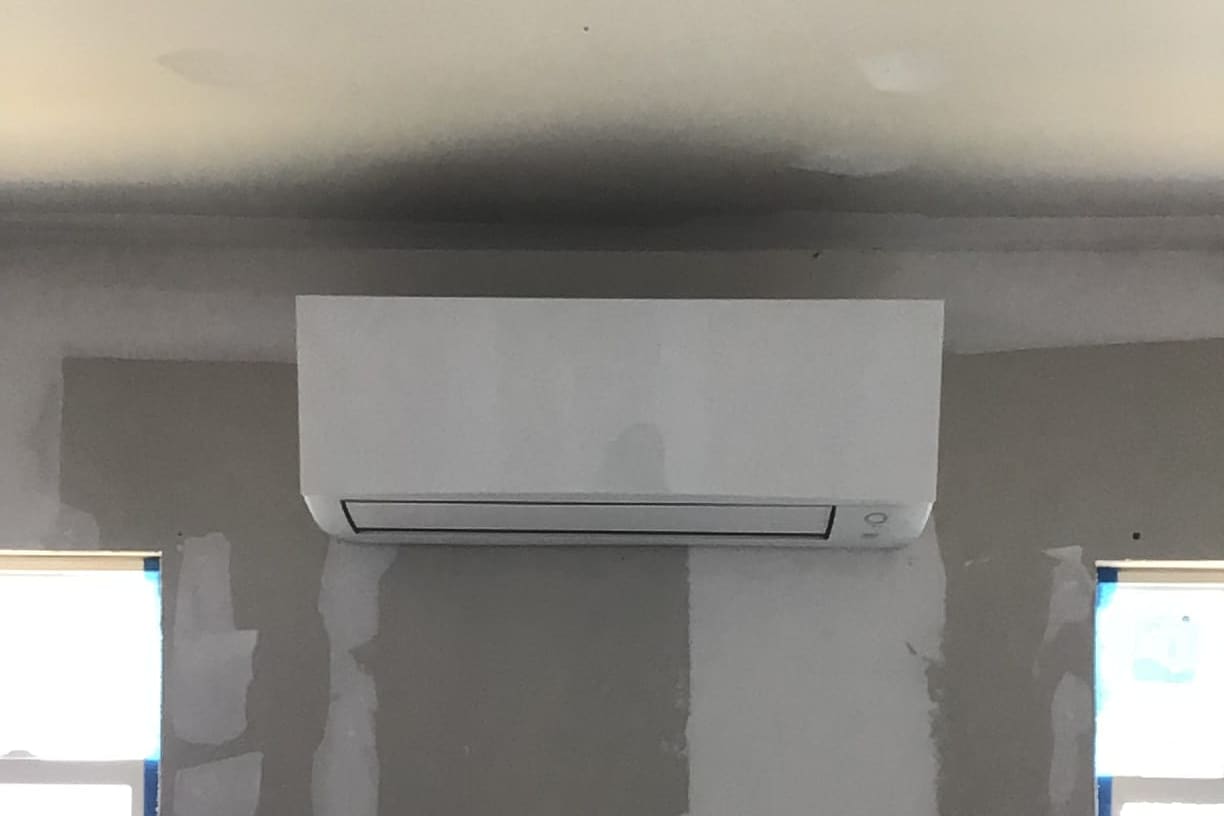 A wall-mounted ductless indoor unit above a new window.